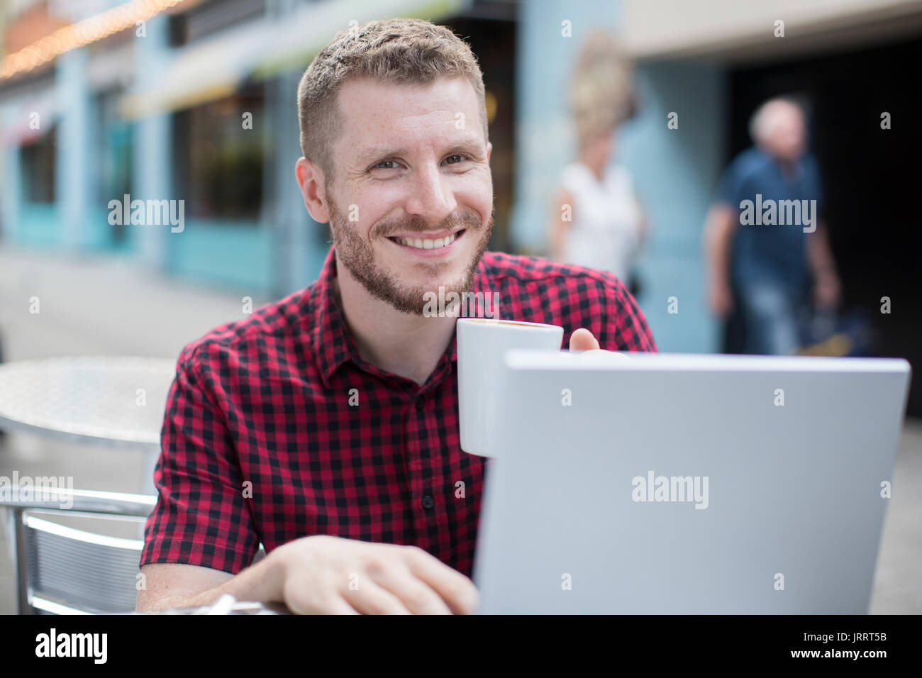 Portrait of Young Man at Outdoor Cafe Working On Laptop Banque D'Images