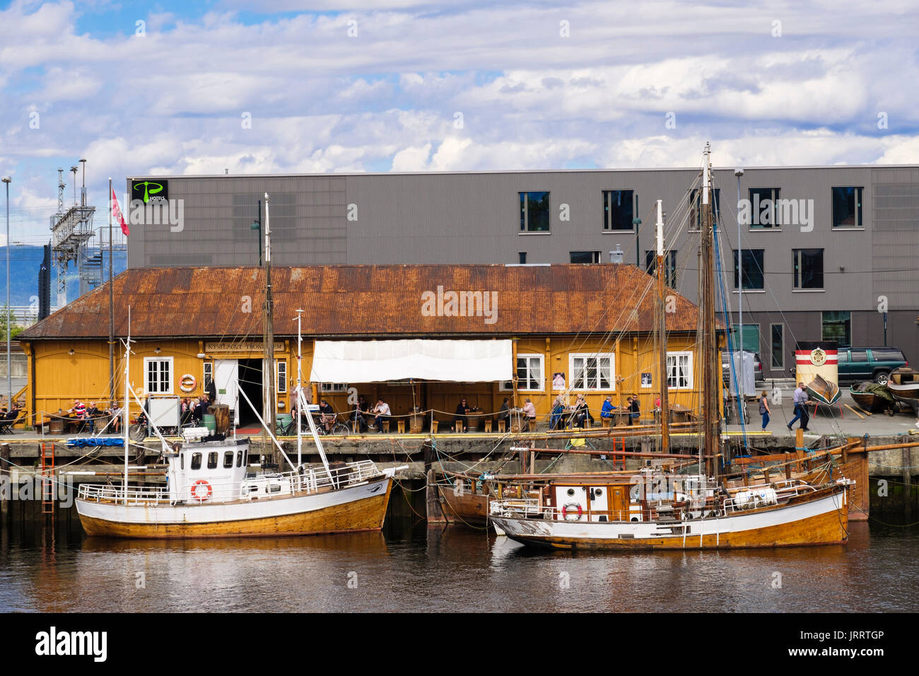 Les bateaux de pêche traditionnels en bois amarré sur la rivière Nidelva quay par riverside cafe. Trondheim, Sør-Trøndelag, Norvège, Scandinavie, Europe Banque D'Images