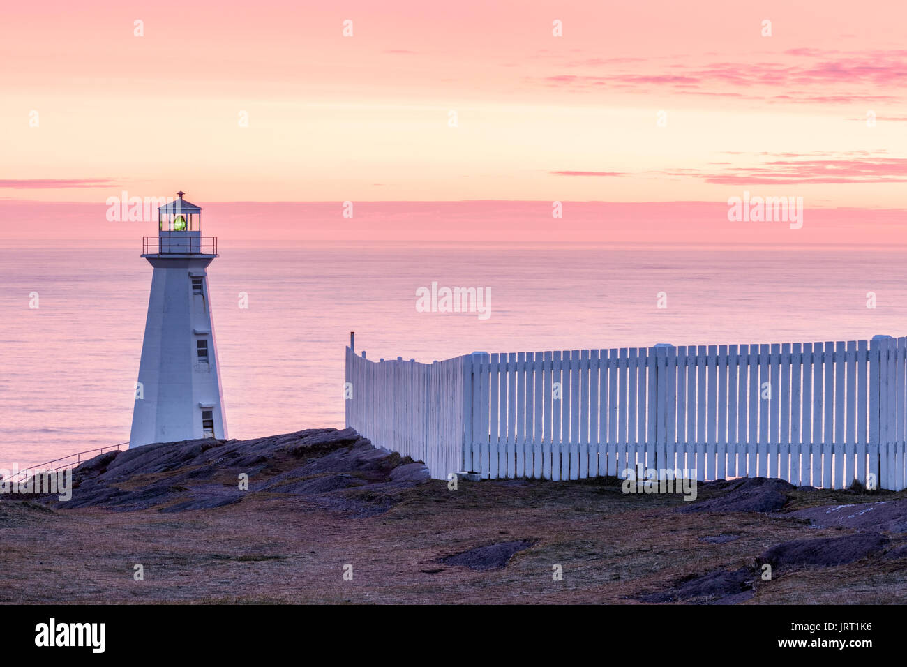 1955 Le phare en béton et une clôture blanche au lieu historique national du Canada du Cap-Spear au lever du soleil. Cape Spear, à Saint-Jean, Terre-Neuve. Banque D'Images