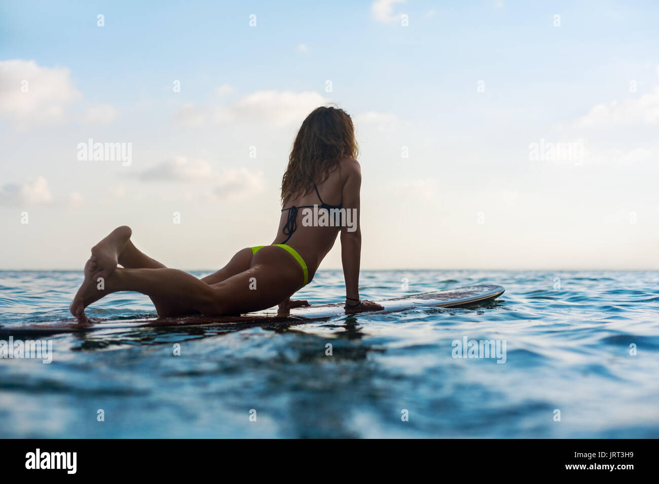 Happy girl in bikini s'amuser avant de se coucher sur surfeur surf surf board, regarder le coucher du soleil Ciel. Les gens dans l'eau sport camp aventure extrême, l'activité. Banque D'Images