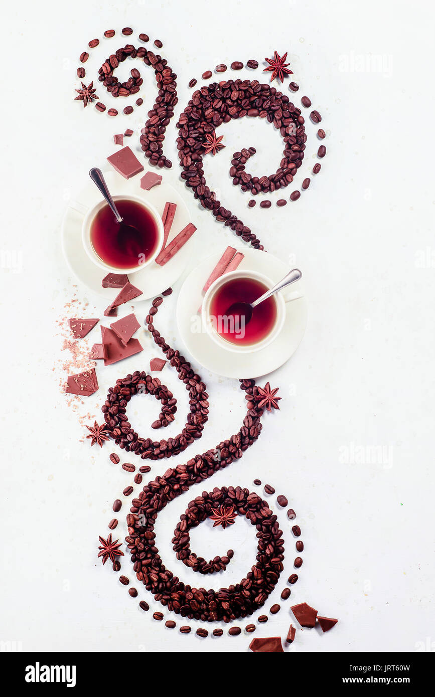 Les grains de café allongé en forme d'un tourbillon avec la coupe, la cannelle, l'anis étoile et les beignes sur un fond blanc Banque D'Images