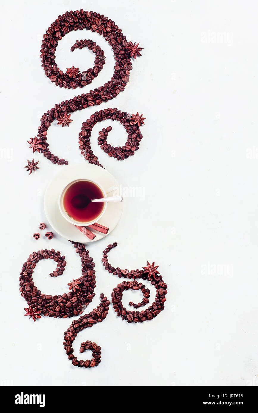 Les grains de café allongé en forme d'un tourbillon avec la coupe, la cannelle, l'anis étoile et les beignes sur un fond blanc Banque D'Images