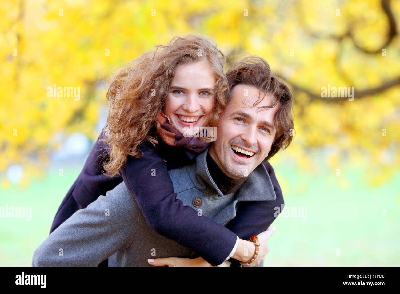L'amour, les relations, la saison et les gens concept - happy young couple having fun in autumn park piggyback ride Banque D'Images