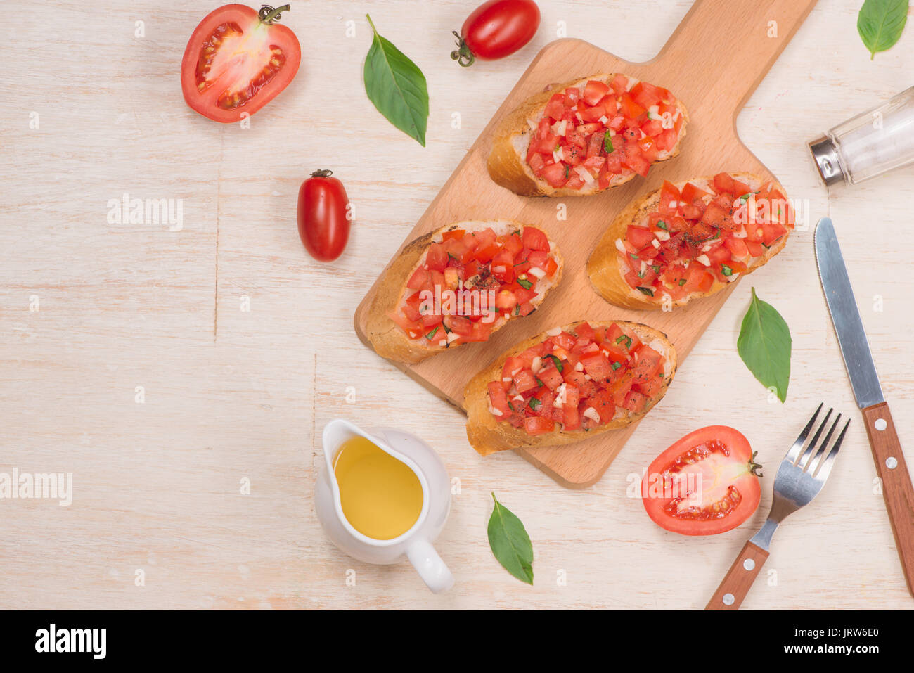 La préparation de délicieux plats italiens Bruschetta aux tomates avec des morceaux de légumes, herbes et l'huile Banque D'Images