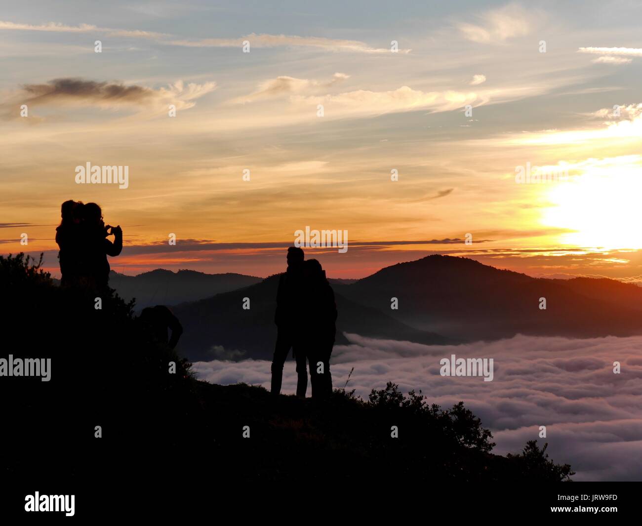 Un couple pose pour une photo devant un lever de soleil impressionnant par l'un des trois lacs de cratère de couleur différente du volcan Kelimutu, Flores, Indonésie Banque D'Images