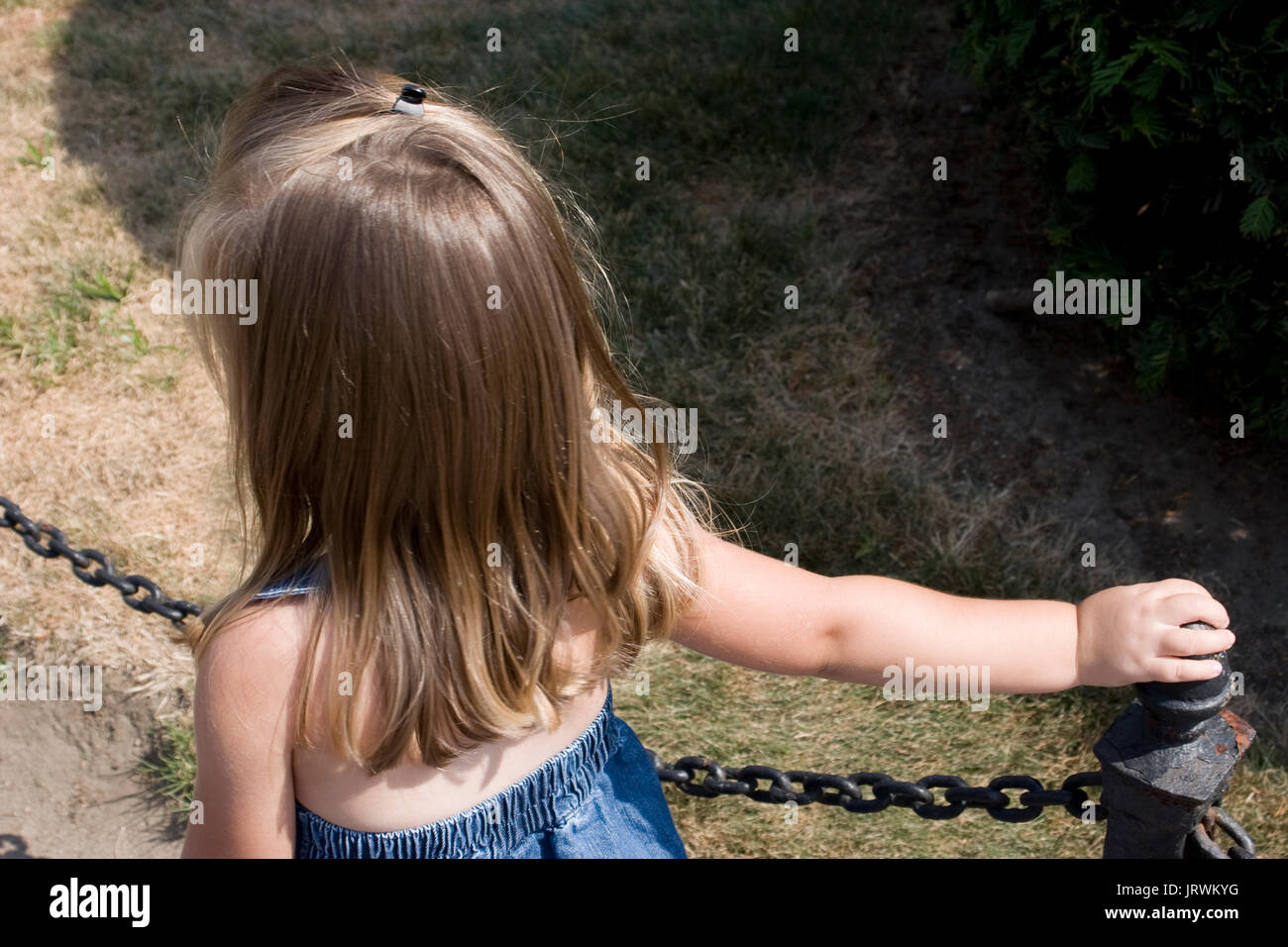 3-year old girl holding sur un poteau de clôture dans un parc Banque D'Images 3-year old girl holding sur un poteau de clôture dans un parc Banque D'Images
