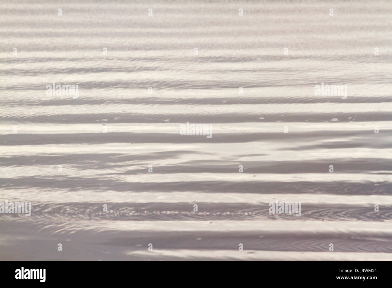 Fermer à la photographie des motifs abstraits sur la plage créé par le sable humide et petites vagues en fin d'après-midi soleil Banque D'Images Fermer à la photographie des motifs abstraits sur la plage créé par le sable humide et petites vagues en fin d'après-midi soleil Banque D'Images