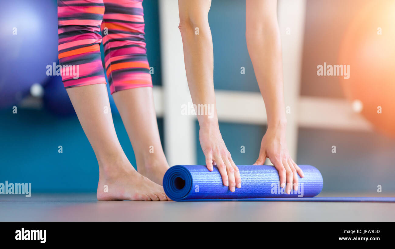 Jeune femme bleu pliable tapis de sol fitness yoga ou après l'entraînement. Vie saine, garder l'ajustement concept. Banque D'Images