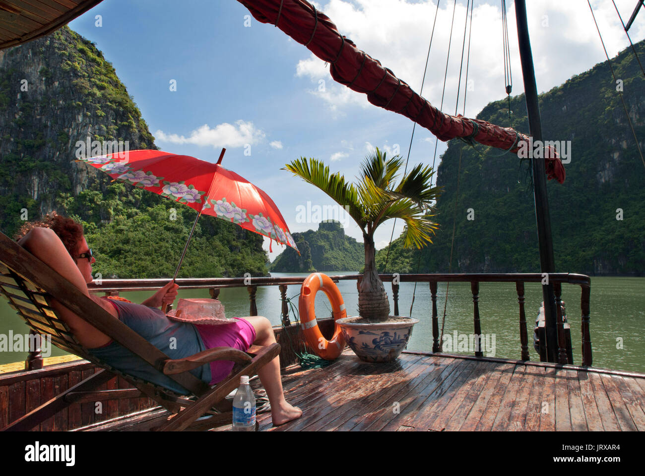Les touristes à l'intérieur de détente une jonque chinoise, la baie d'Halong excursion en bateau de tourisme, Vietnam. junk, bateau naviguant entre les montagnes de calcaire karstique à cat ba nationa Banque D'Images