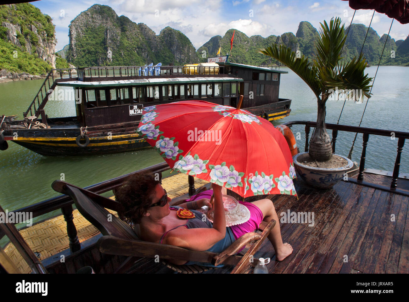 Les touristes à l'intérieur de détente une jonque chinoise, la baie d'Halong excursion en bateau de tourisme, Vietnam. junk, bateau naviguant entre les montagnes de calcaire karstique à cat ba nationa Banque D'Images