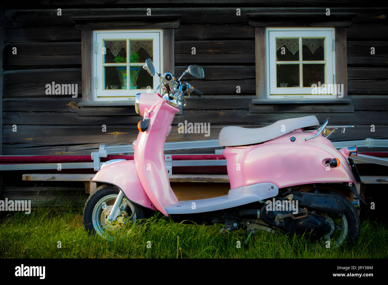 Scooter rose est garée près de l'ancien bâtiment en bois Banque D'Images