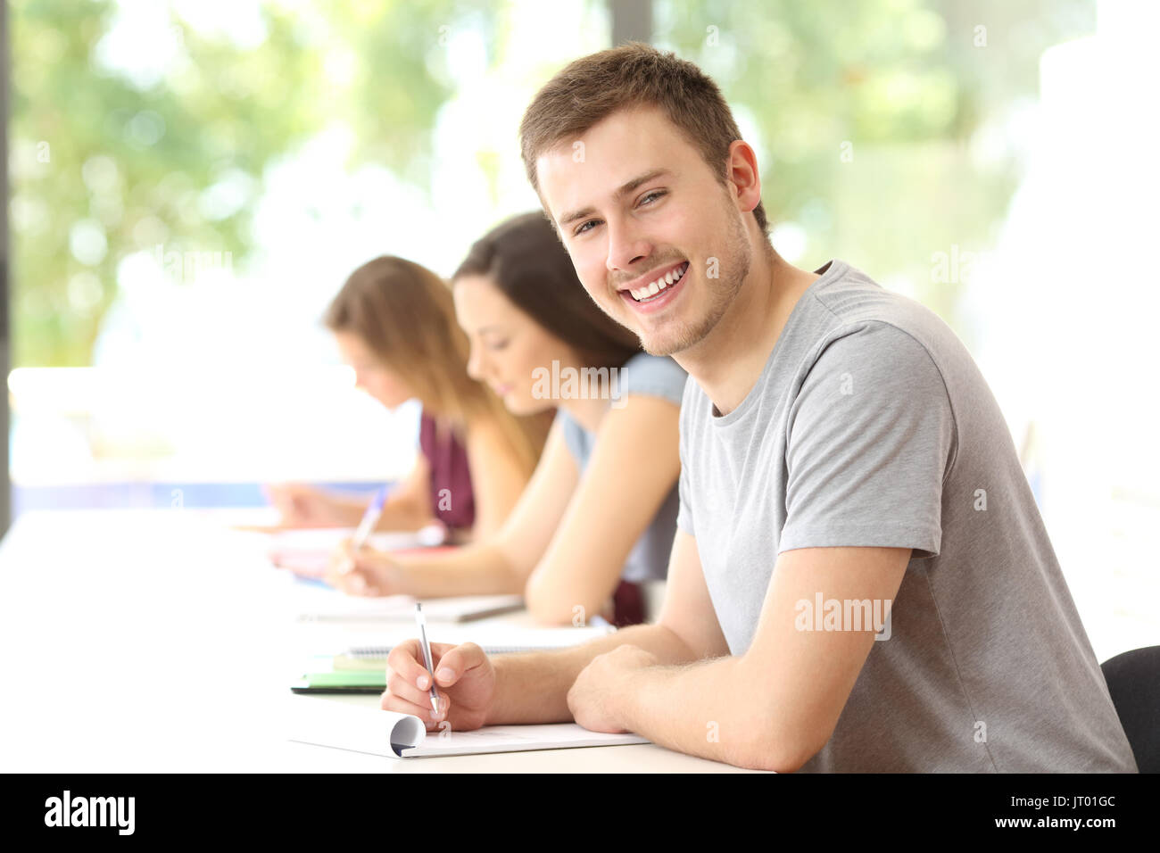 Happy student boy posing in a classroom looking at you Banque D'Images