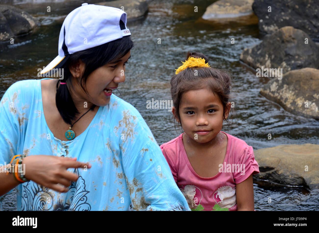 Les femmes thaïlandaises voyageur prendre des photos avec les enfants laotiens fille assis sur la pierre en stream de Tad Pha Suam cascade de Plateau des Bolavens le 2 mai 2015 à Pa Banque D'Images