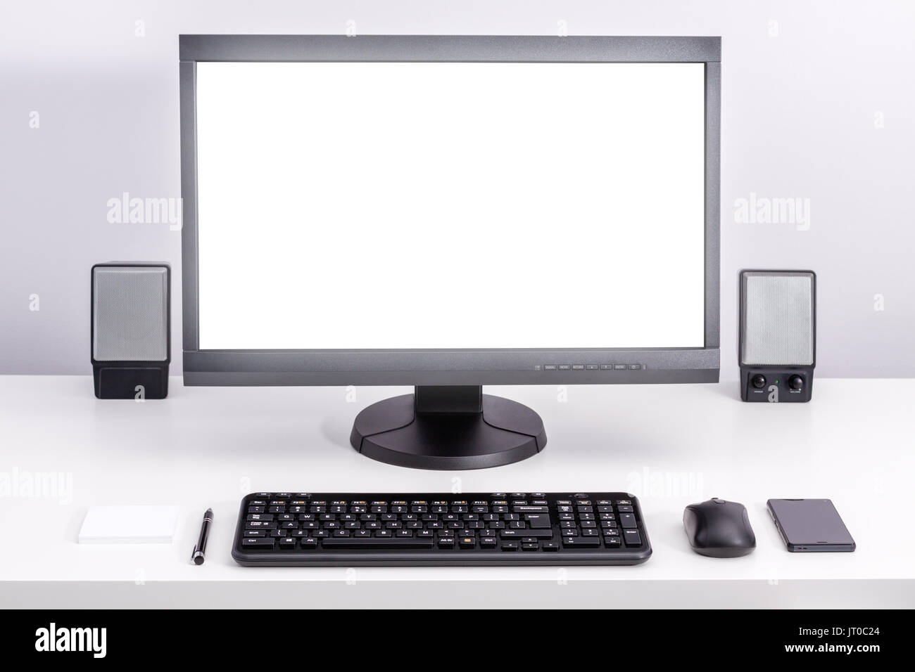 Moniteur pc blanc vide sur séjour 24, autour de l'ordre d'espace pour travailler avec clavier, souris d'ordinateur, smartphone, haut-parleurs, plume et notes adhésives. Banque D'Images