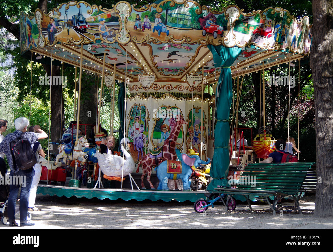 Enfants assis sur un petit carrousel, Square des Batignolles, Paris France, tandis que les parents et les grands-parents aussi, d'admirer et de les photographier. Banque D'Images
