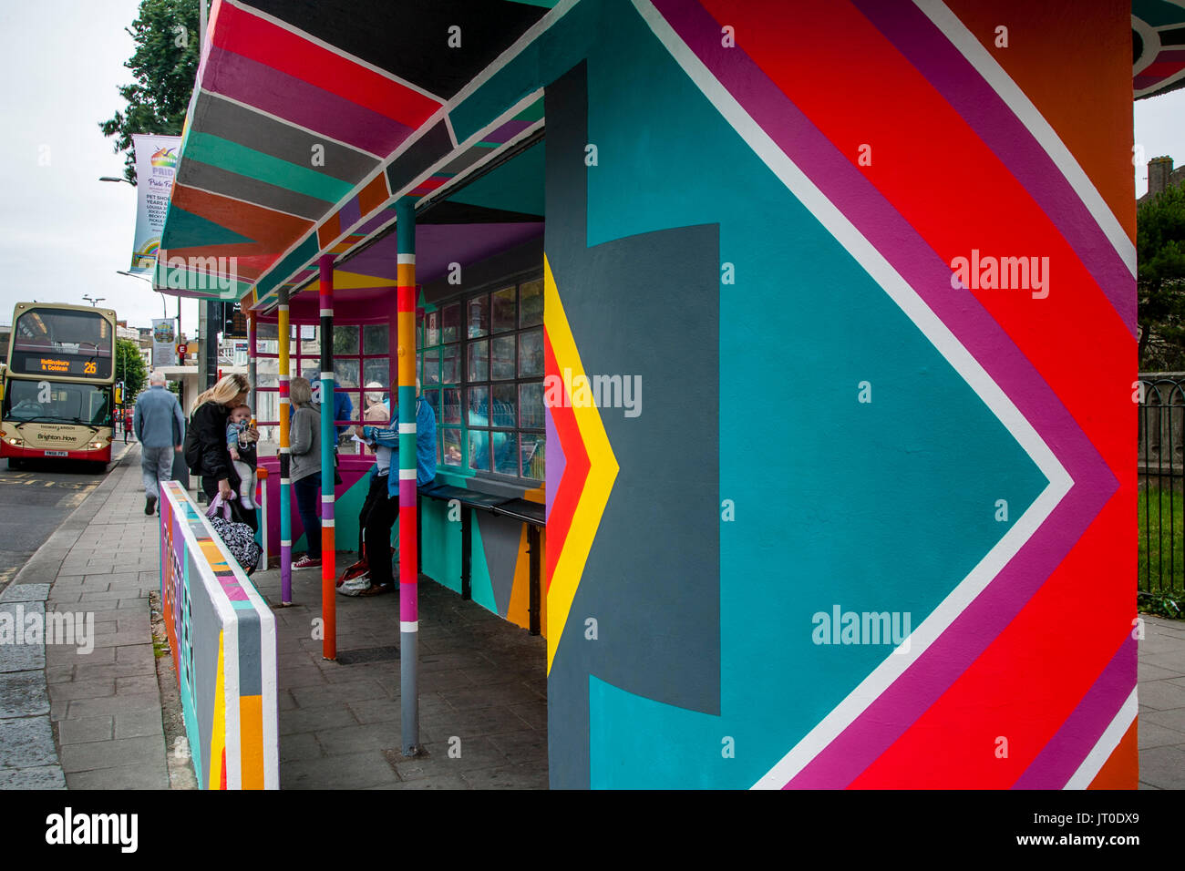 Personnes en attente d'un bus à l'intérieur d'un abri bus peintes de couleurs vives, Brighton, Sussex, UK Banque D'Images