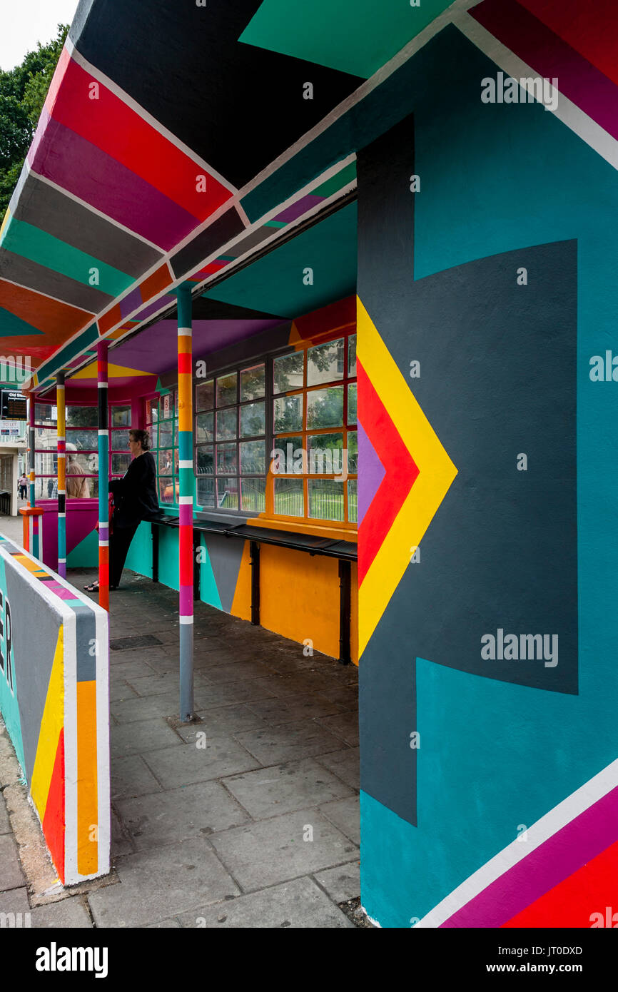 Personnes en attente d'un bus à l'intérieur d'un abri bus peintes de couleurs vives, Brighton, Sussex, UK Banque D'Images