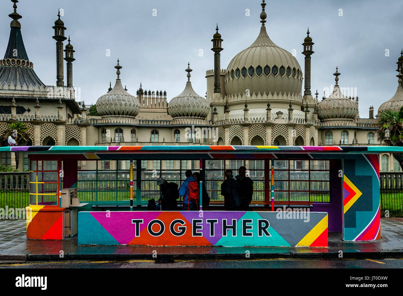 Personnes en attente d'un bus à l'intérieur d'un abri bus peintes de couleurs vives, Brighton, Sussex, UK Banque D'Images