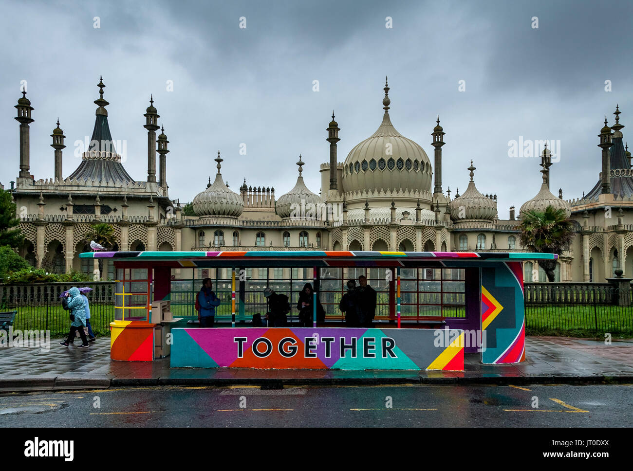 Personnes en attente d'un bus à l'intérieur d'un abri bus peintes de couleurs vives, Brighton, Sussex, UK Banque D'Images