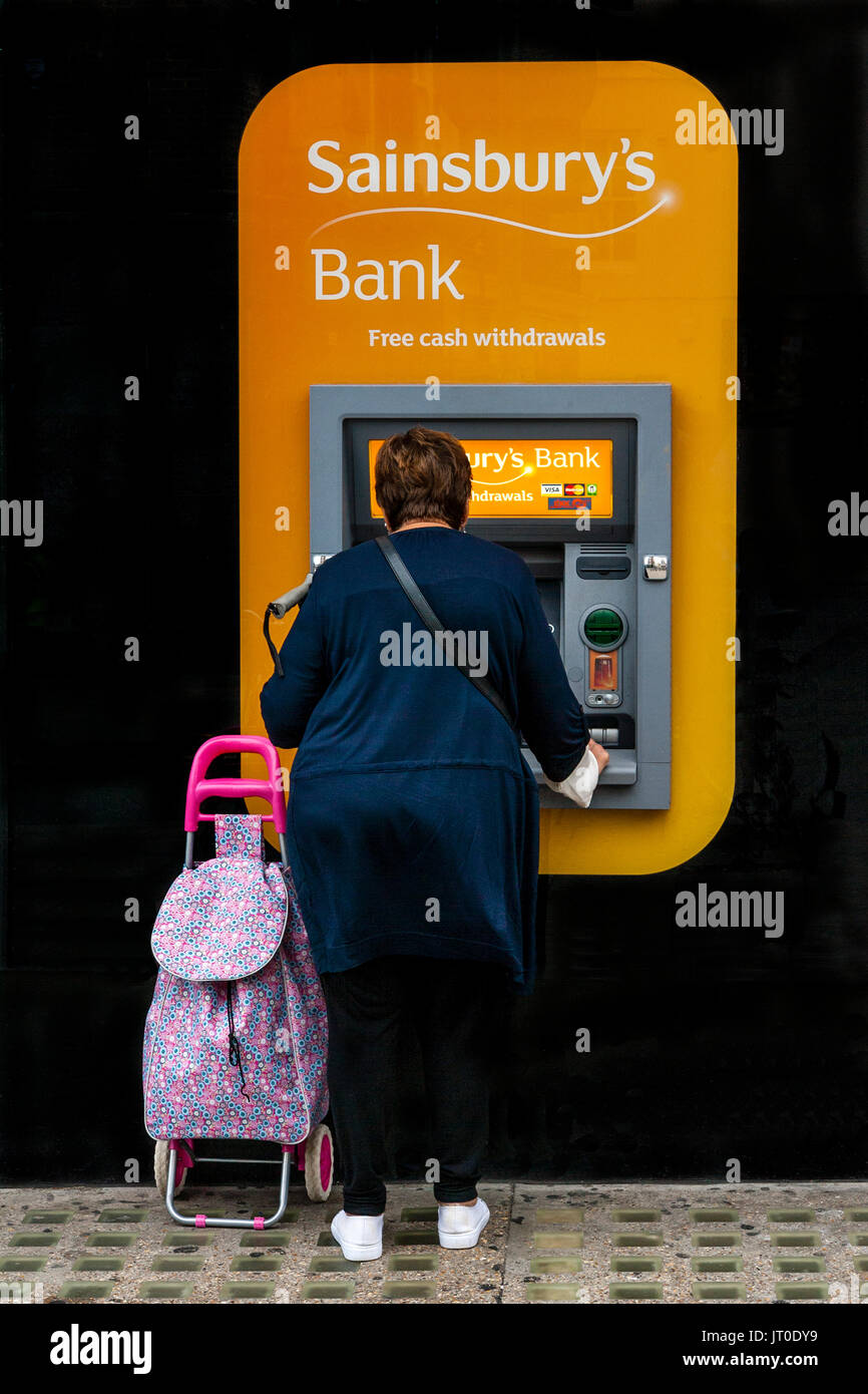 Une femme retire de l'argent à un guichet automatique, Brighton, Sussex, UK Banque D'Images