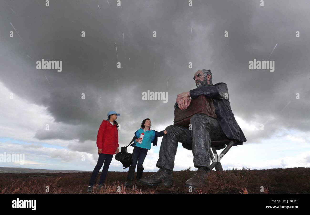 Hyunbea 12 Jung de Castleton et Eve Clarke de Hexham 11 regarder la homme assis, une sculpture de 3 mètres par Sean Henry, à Castleton Rigg, près de Westerdale dans le North York Moors National Park. Banque D'Images