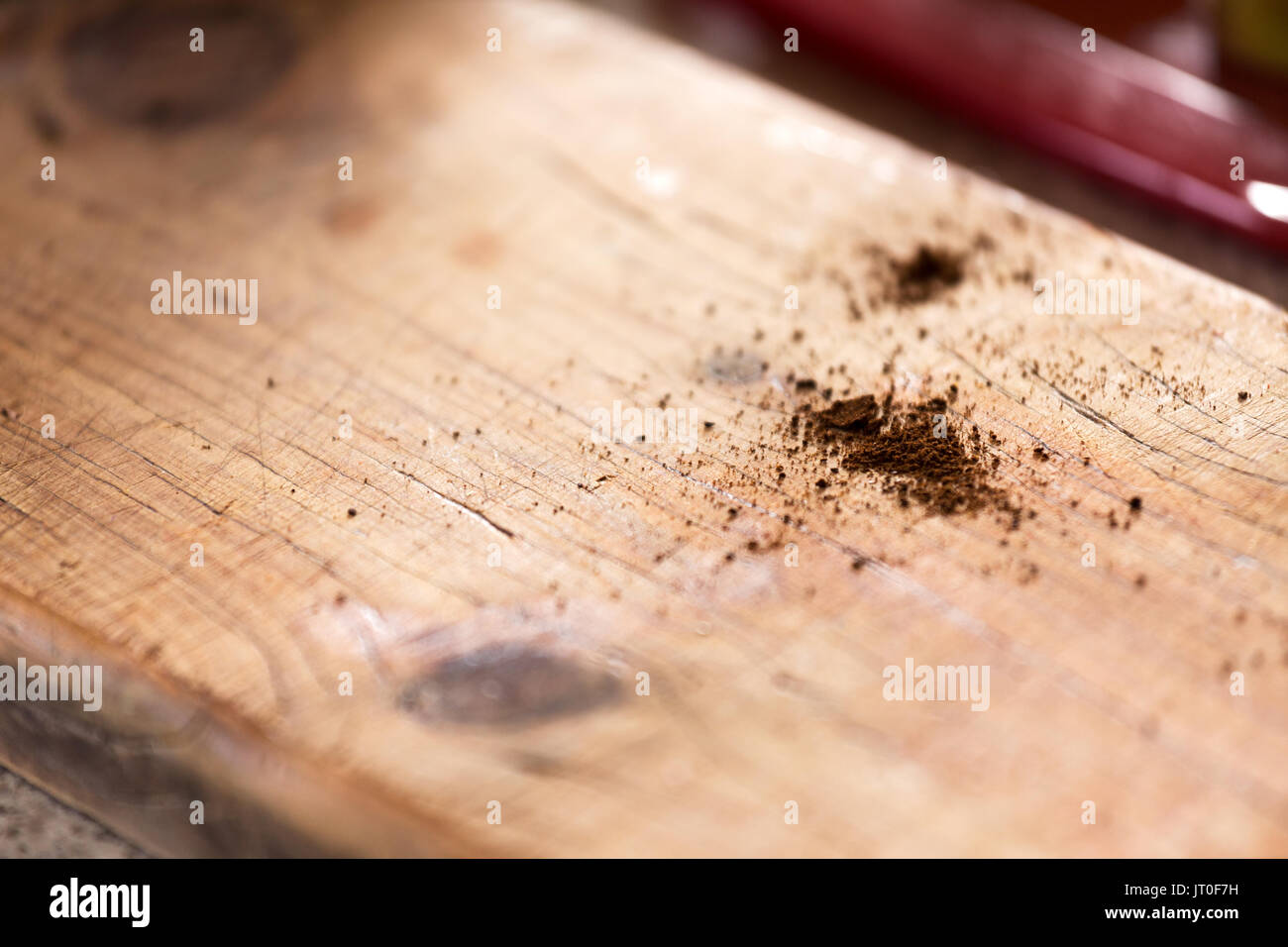 Un abrégé close up de moutures de café renversé sur un banc de bois rustique cafe haut avec une faible profondeur de champ et l'espace pour le texte ou contenu. Banque D'Images