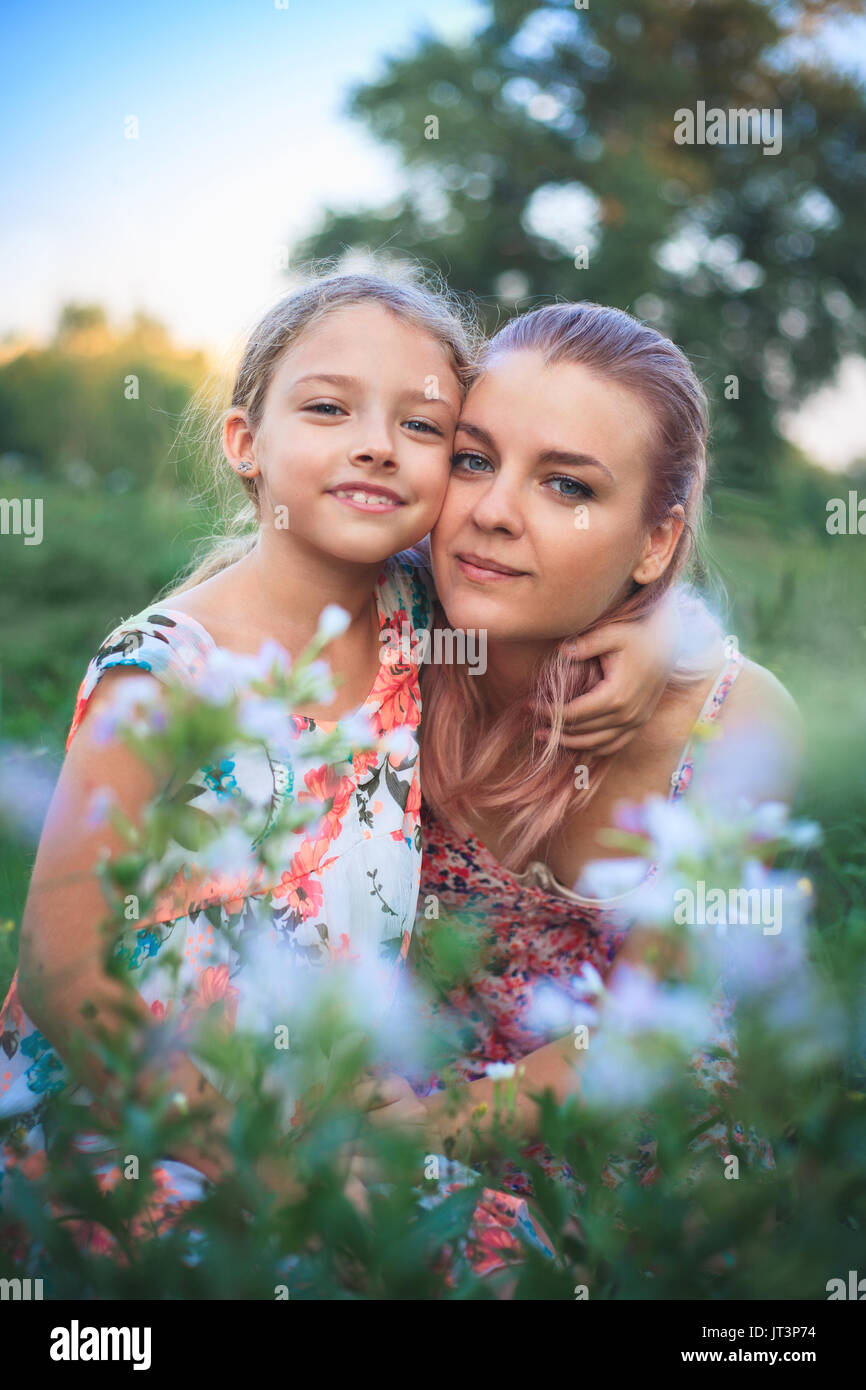 Ortrait de mère et fille sur la nature en fleurs sur une belle journée d'été. Banque D'Images