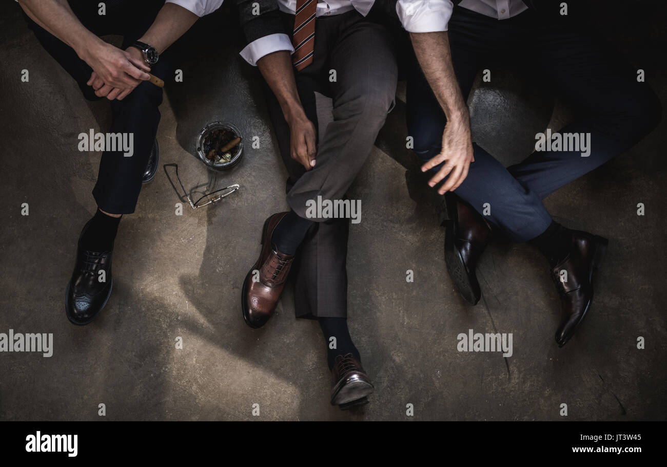 Cropped shot de groupe d'hommes assis sur le plancher ensemble Banque D'Images