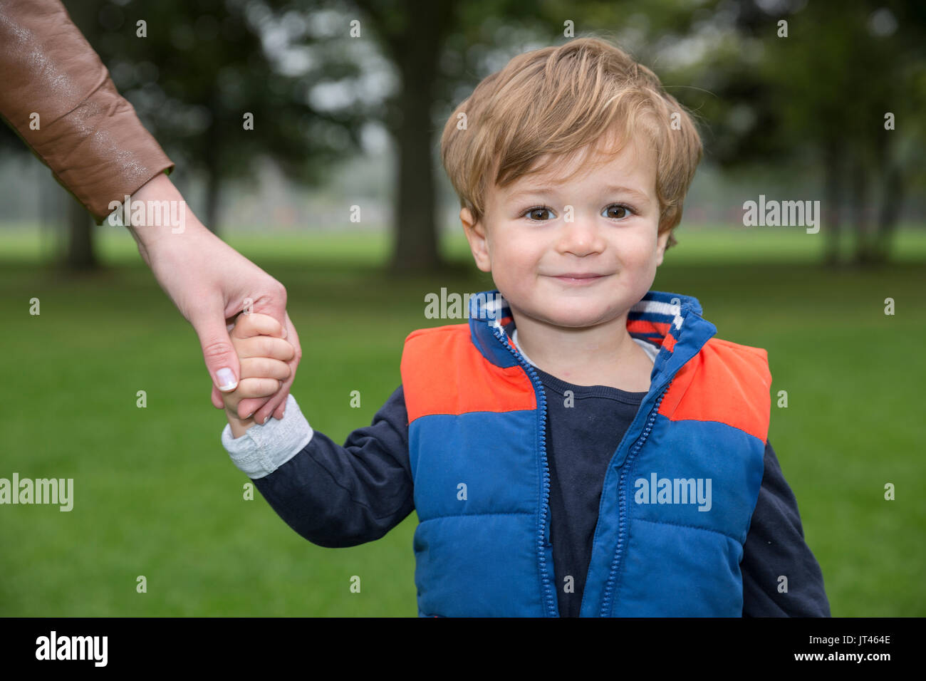 Portrait d'un jeune garçon se tenant la main avec sa mère, en plein air dans le parc. Banque D'Images