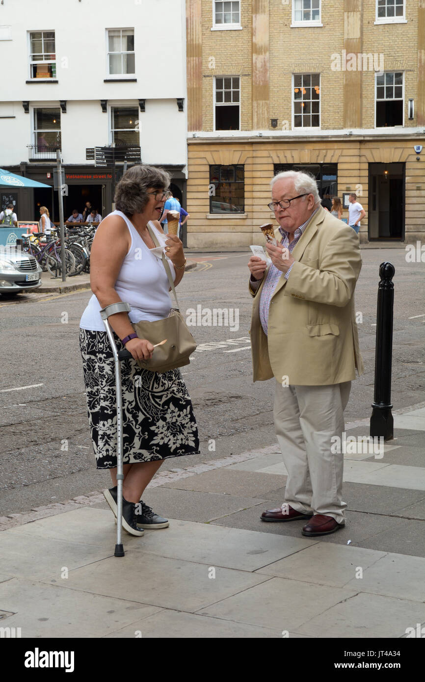 Couple de personnes âgées de manger des glaces dans les rues de Cambridge Cambridgeshire Angleterre Banque D'Images