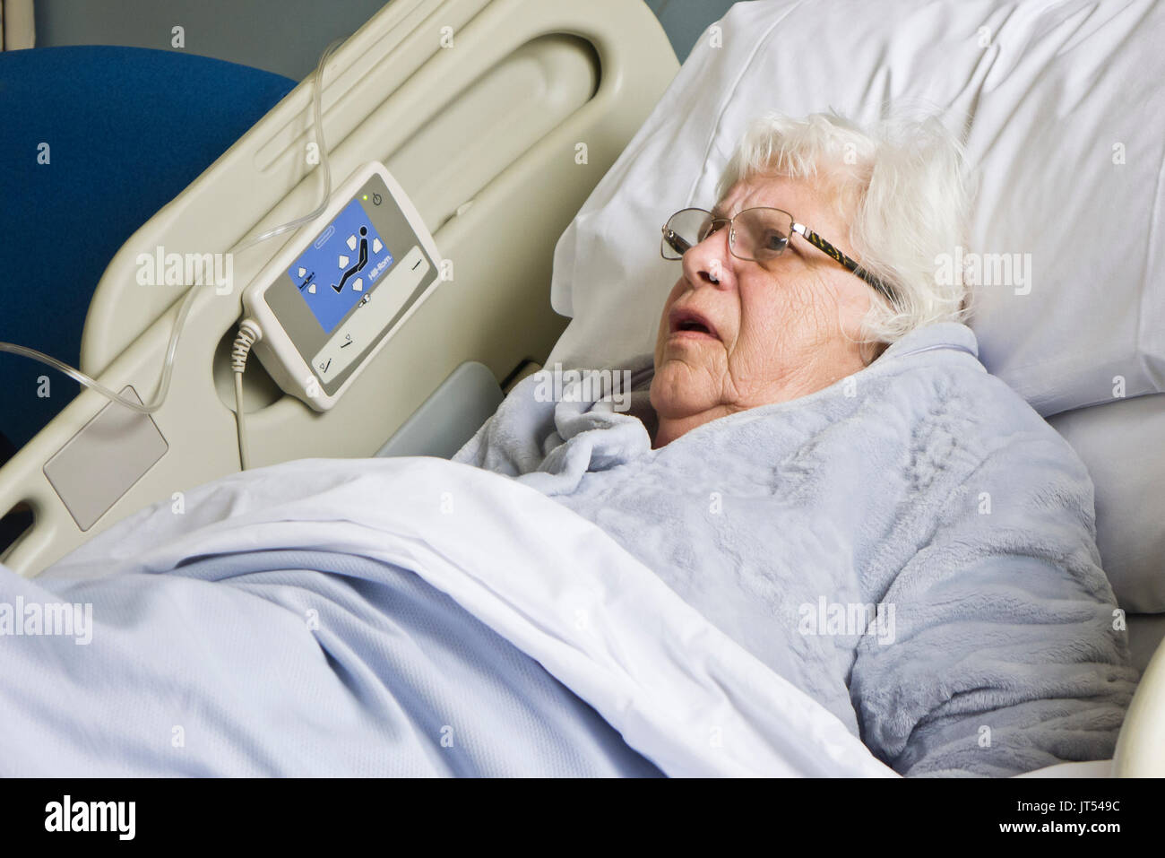 Une vieille dame dans un lit d'hôpital en attente d'un paquet de soins pour permettre sa libération. Banque D'Images