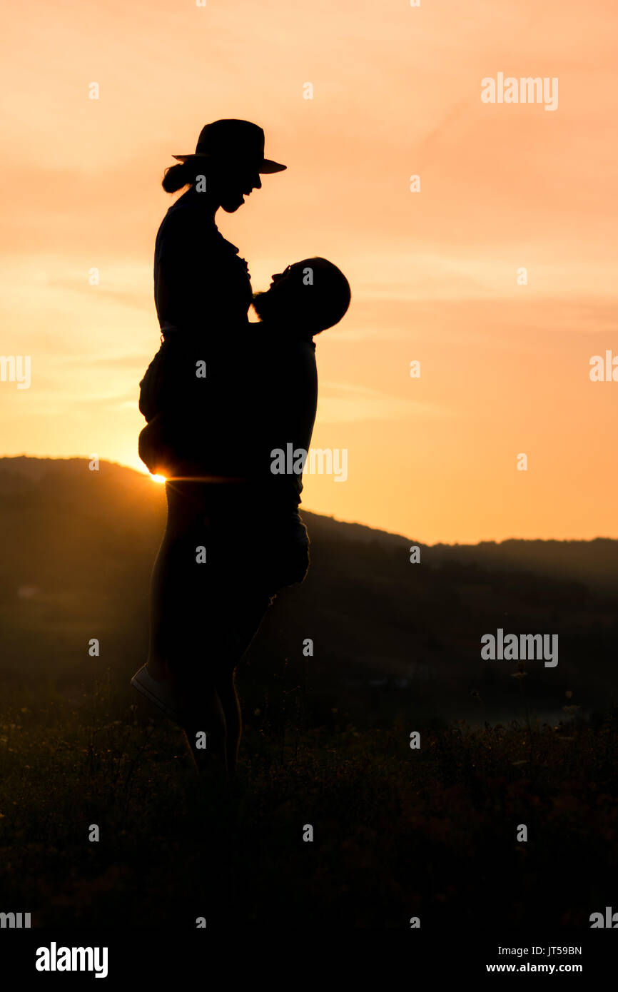Heureux couple silhouette avec coucher de soleil romantique avec golden sky Banque D'Images