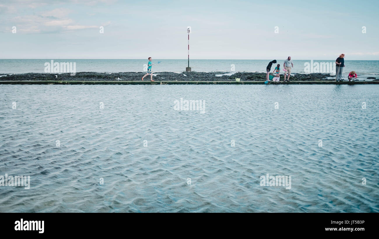 Les familles bénéficiant de la pêche des crabes sur la plage piscine à Broadstairs, Kent sous le soleil d'été. Banque D'Images