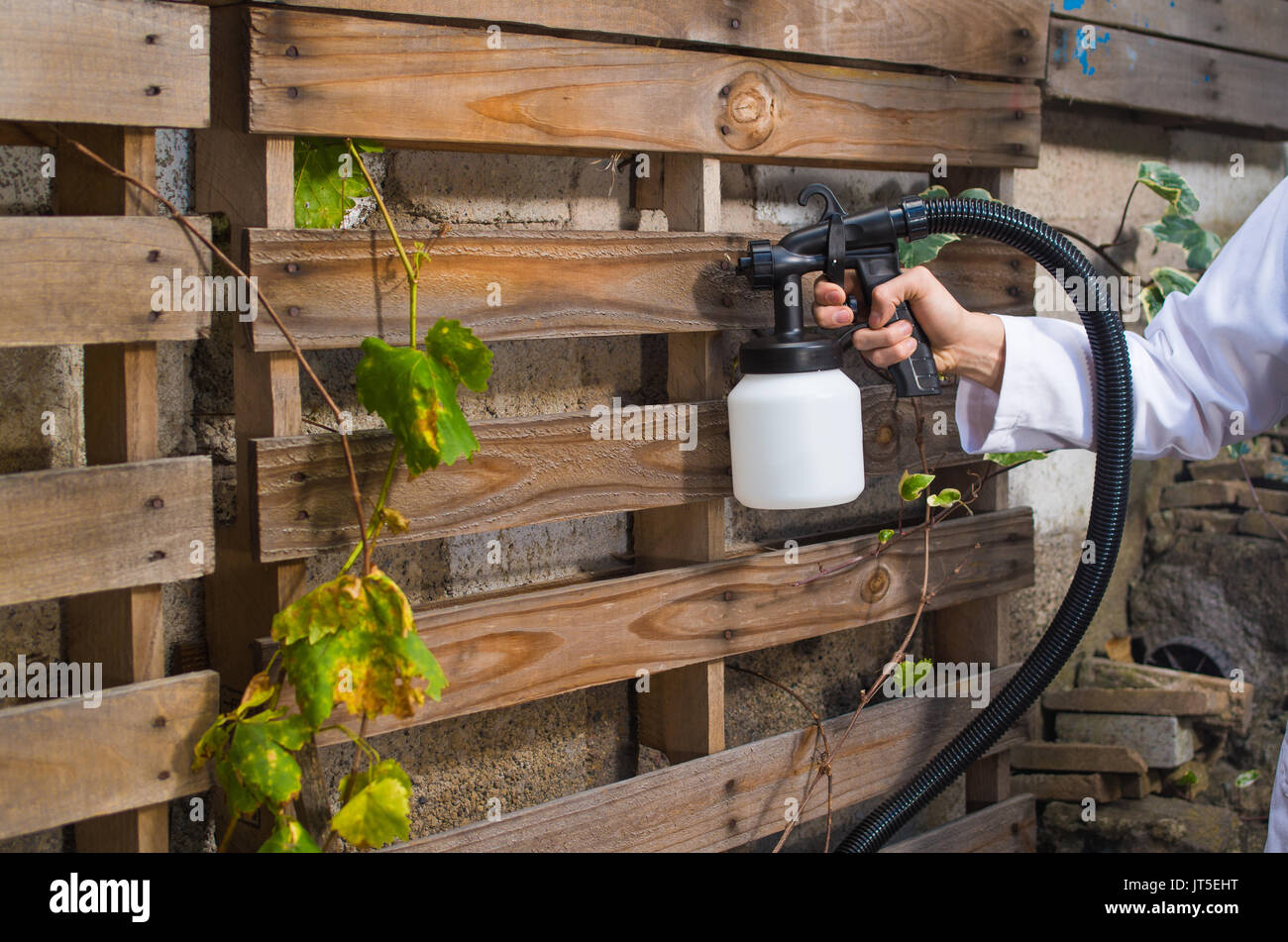 Close up d'un travailleur de la construction à l'aide du pistolet de pulvérisation de peinture en plein air dans une structure en bois de Banque D'Images