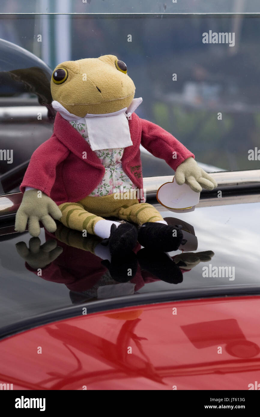 Crapaud jouets anciens assis sur une voiture classique britannique Banque D'Images