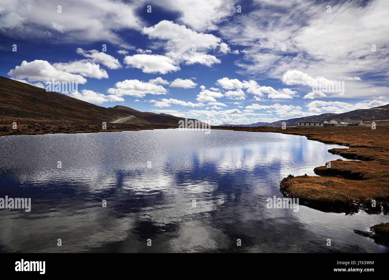 Grand lac dans la prairie jaune avec la réflexion de nuages blancs du ciel bleu au niveau national Yading, Daocheng, province du Sichuan, Yunnan Banque D'Images