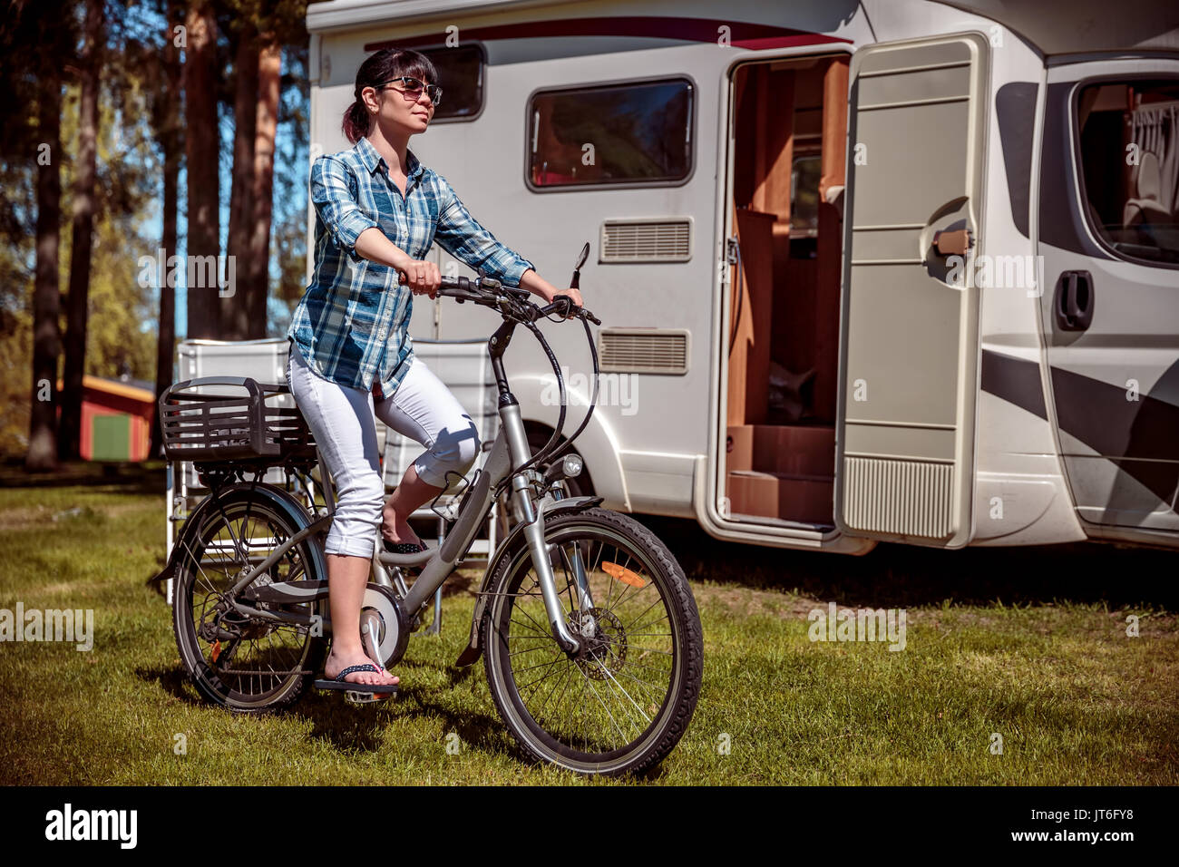Femme sur vélo électrique reposant sur le camping. Vacances famille vacances, voyages voyage en camping-car, caravane location de vacances. Banque D'Images