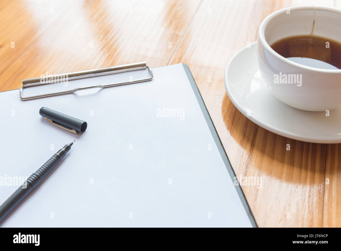 Une tasse de thé ou de café et d'un stylo et ordinateur portable sur un bureau en bois bureau en Banque D'Images