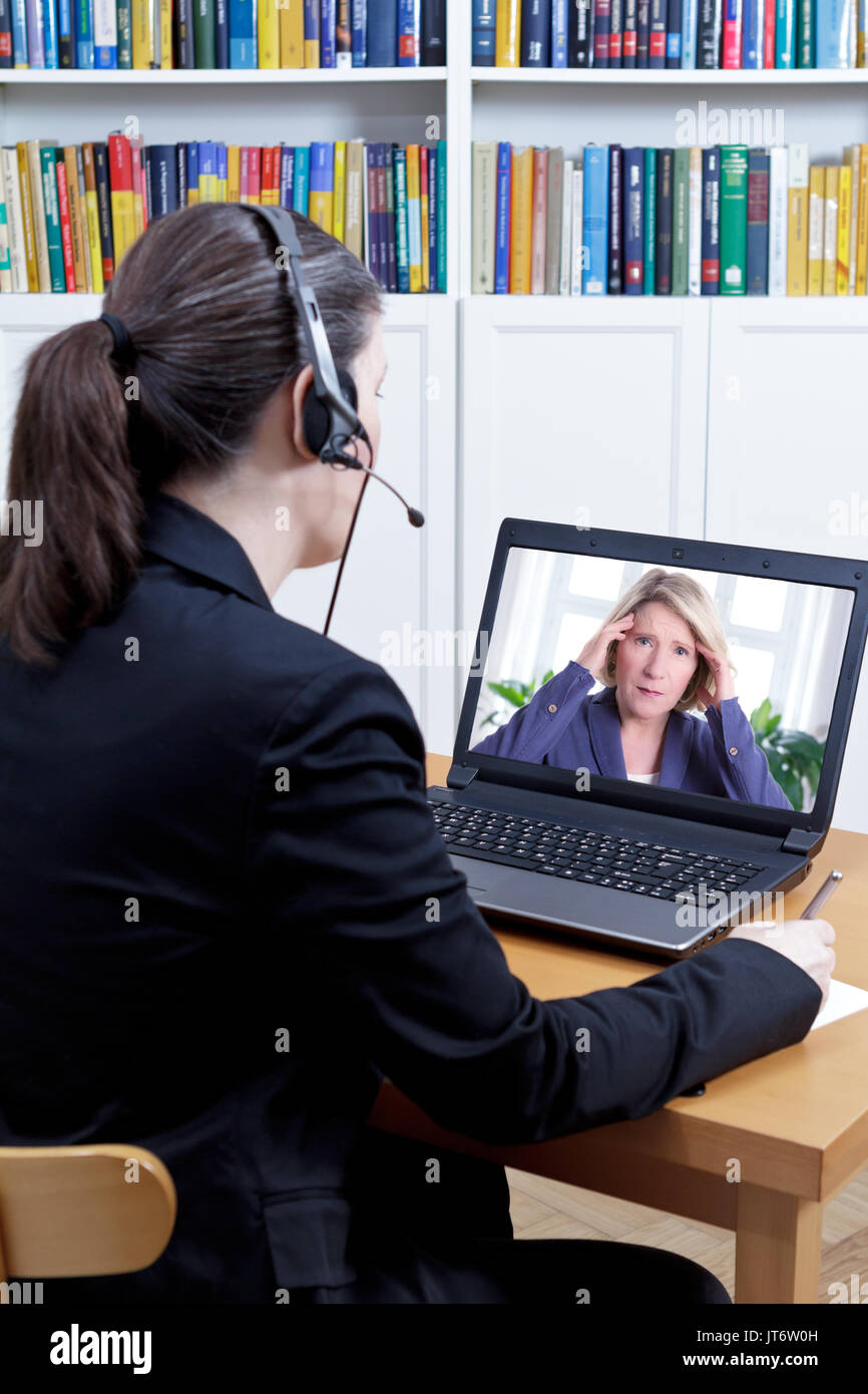 Psychologue dans son bureau devant son ordinateur, à parler à une femme extrêmement a souligné au cours d'un appel vidéo en direct ou chat, counseling en ligne concept Banque D'Images