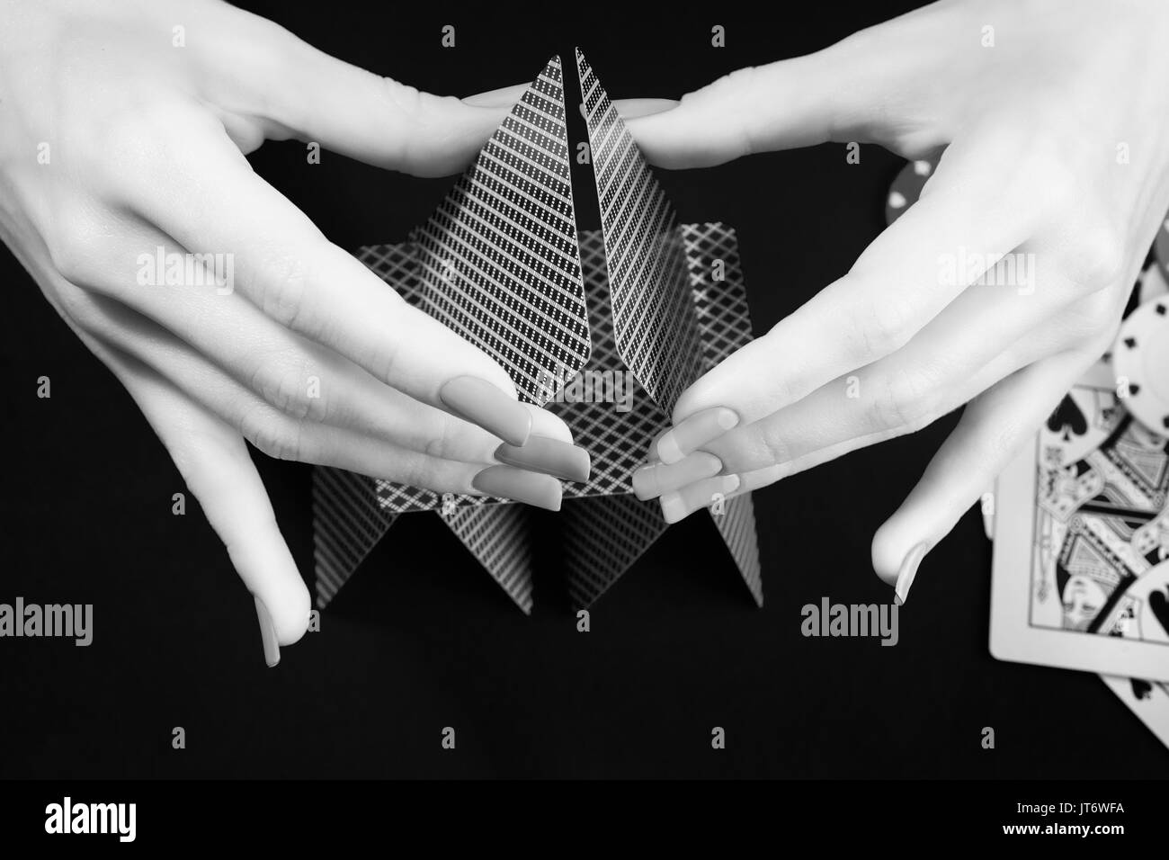 Femme mains assemblage château de cartes. Photo en noir et blanc. Le jeu, casino, fortune et chance thème Banque D'Images