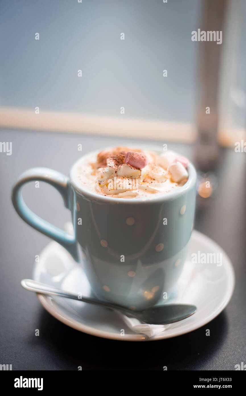 Burley, Hampshire, Royaume-Uni. Une tasse de chocolat chaud avec des guimauves décorées dans un mug à pois avec une cuillère et soucoupe volante. Banque D'Images