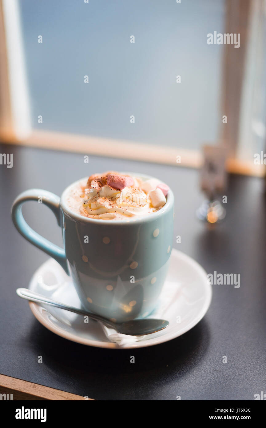 Burley, Hampshire, Royaume-Uni. Une tasse de chocolat chaud avec des guimauves décorées dans un mug à pois avec une cuillère et soucoupe volante. Banque D'Images