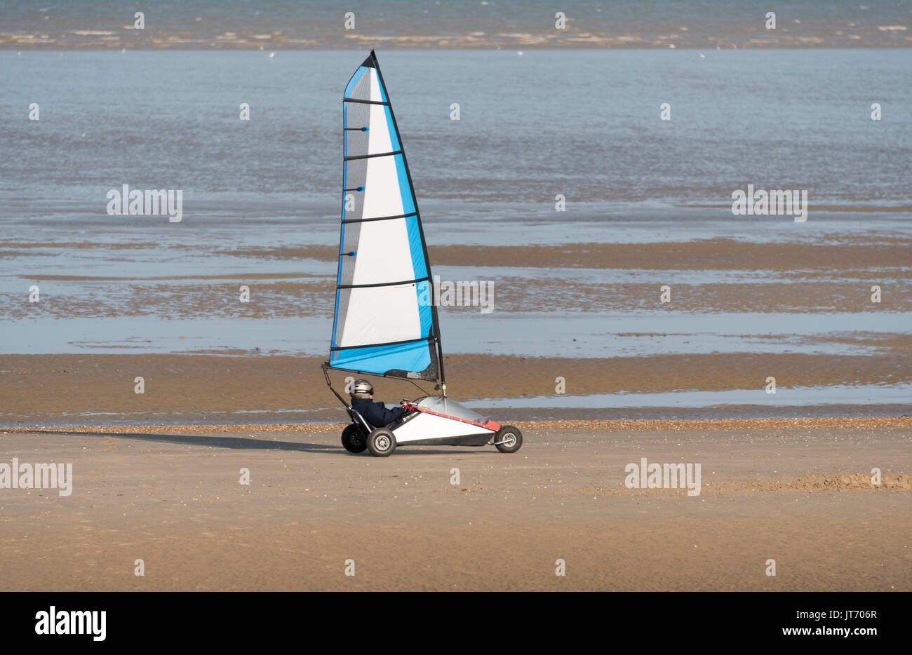 Le pilote dirige son char à voile le long d'une plage de sable. Banque D'Images