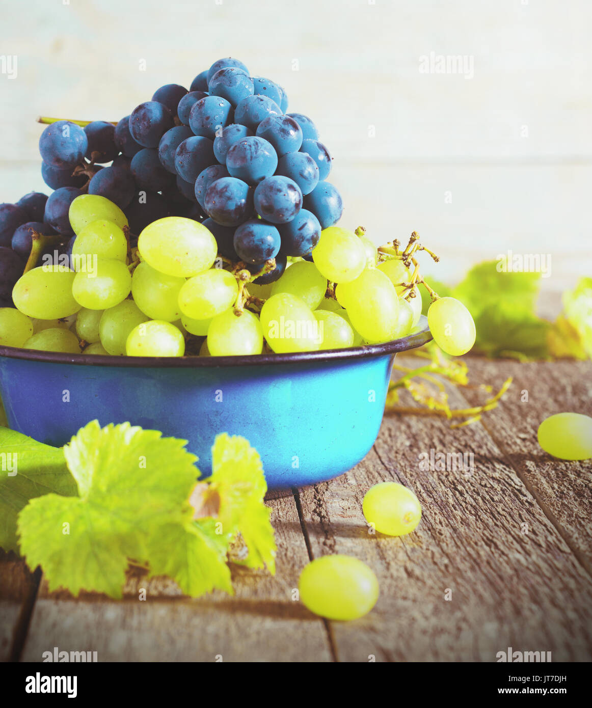 Raisins verts et bleus dans un bol en métal sur un fond de bois Banque D'Images