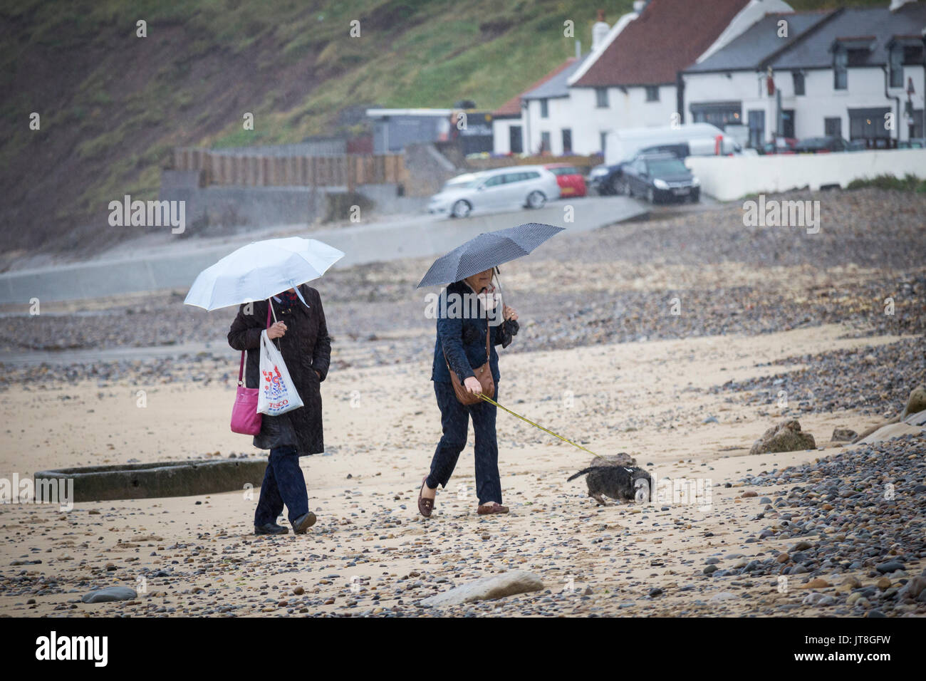 Dog walker/marcheurs walking on beach sous la pluie. UK Banque D'Images