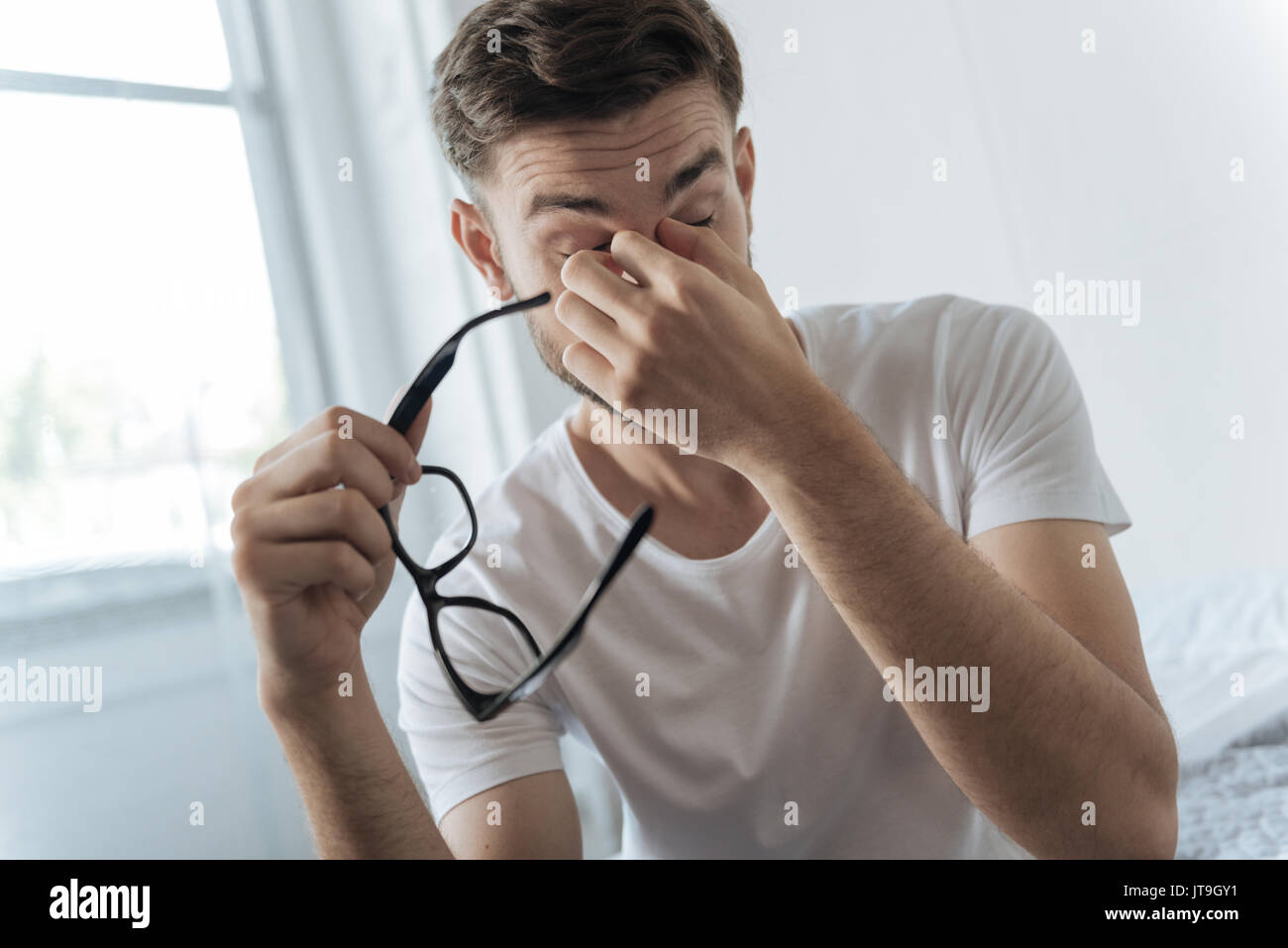 Triste homme fatigué tenant ses lunettes Banque D'Images