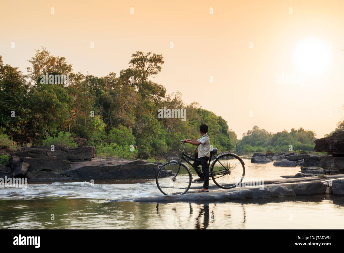School boy on a bicycle traversant une rivière sur son chemin de l'école, Chi Phat, Koh Kong, le Cambodge, l'Indochine, l'Asie du Sud-Est, Asie Banque D'Images