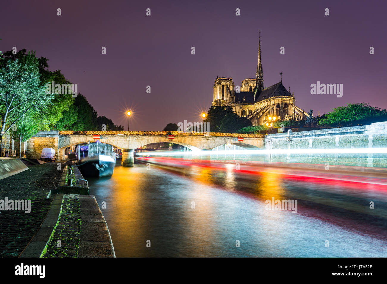 Une longue exposition d'un bateau sur la Seine en passant la cathédrale Notre Dame sur une soirée dans Paris, France, Europe Banque D'Images