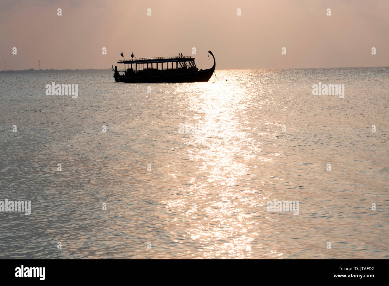 Bateau en bois en silhouette au coucher du soleil, au large de Dhuni Kolhu, l'atoll de Baa, République des Maldives, l'Océan Indien, l'Asie Banque D'Images