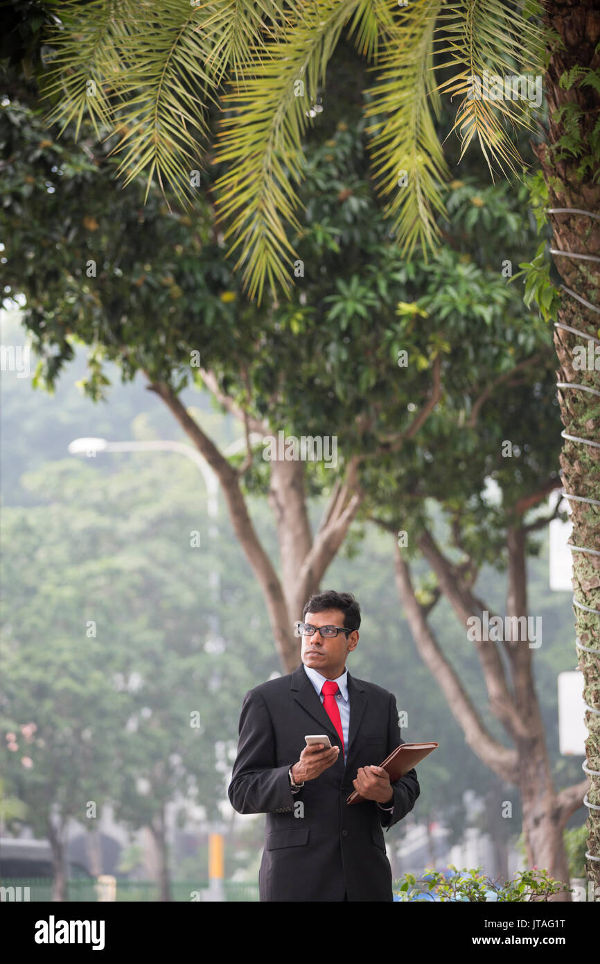 L'homme d'affaires indien à l'aide de son téléphone intelligent à l'extérieur, dans la ville d'Asie. Banque D'Images